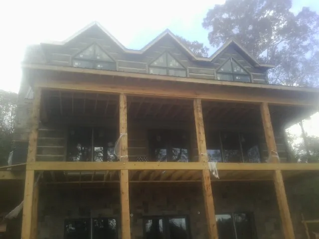 Dormers and porch framing on a large log home under construction — Roof Coating work by our crew in Taunton