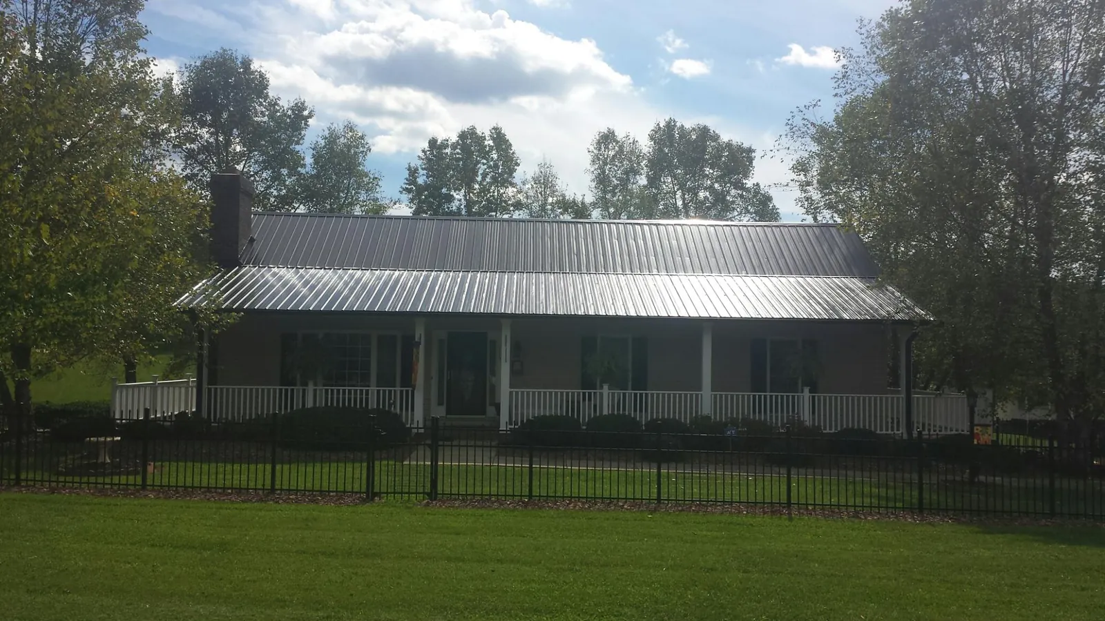 Gray metal roof on a brick ranch with a full width front porch — Gutter Guard Installation work by our crew in Taunton