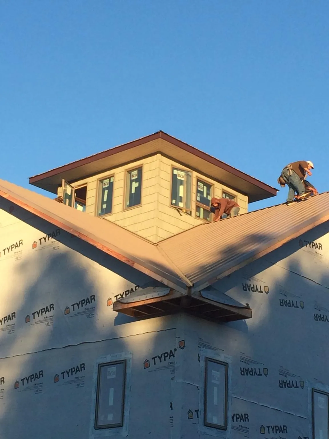 Roofers working around a rooftop cupola on a new metal roof at sunset — Roof Waterproofing in Taunton by Roofing Brothers